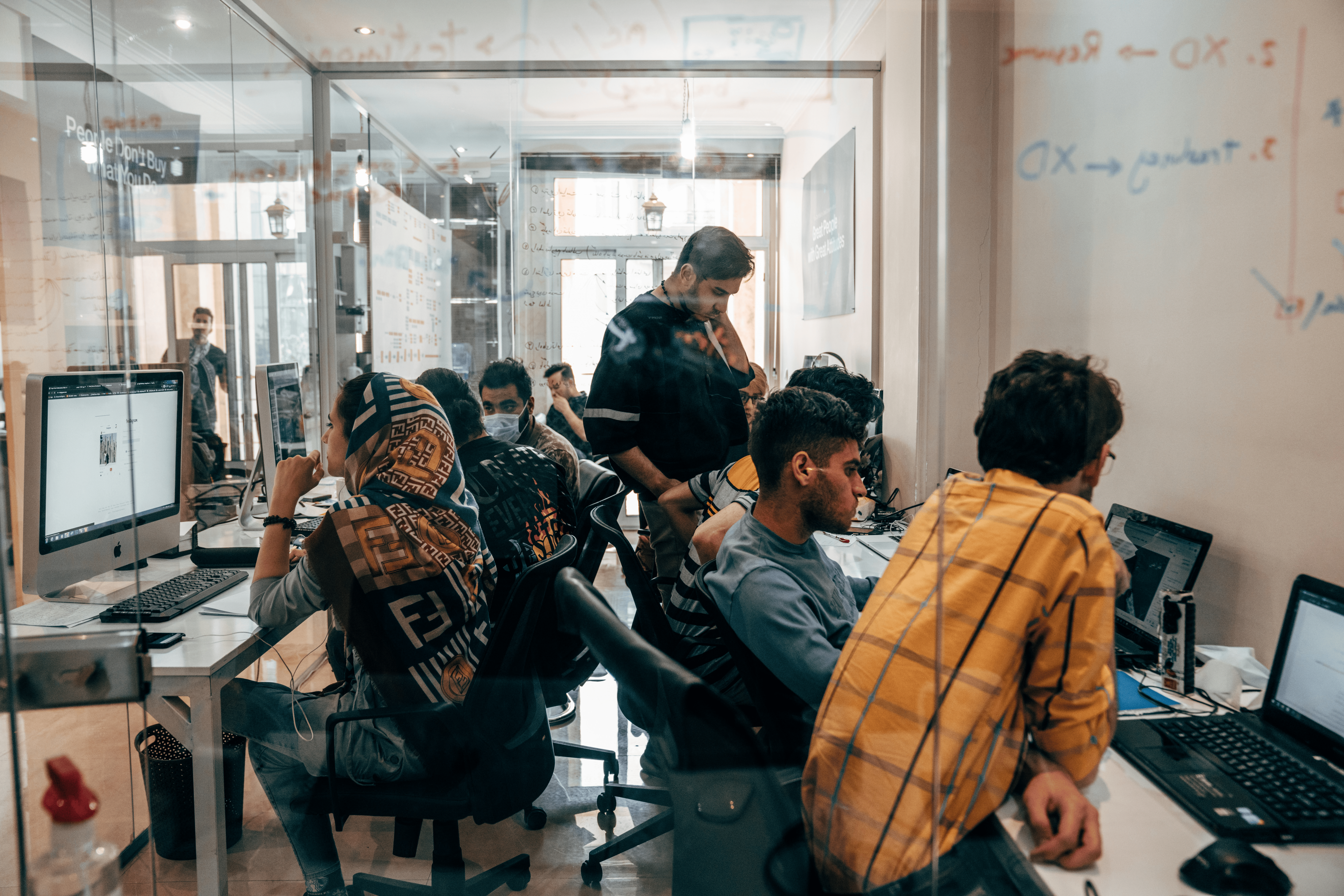Image shows a photo of an office with people working and talking to each other.