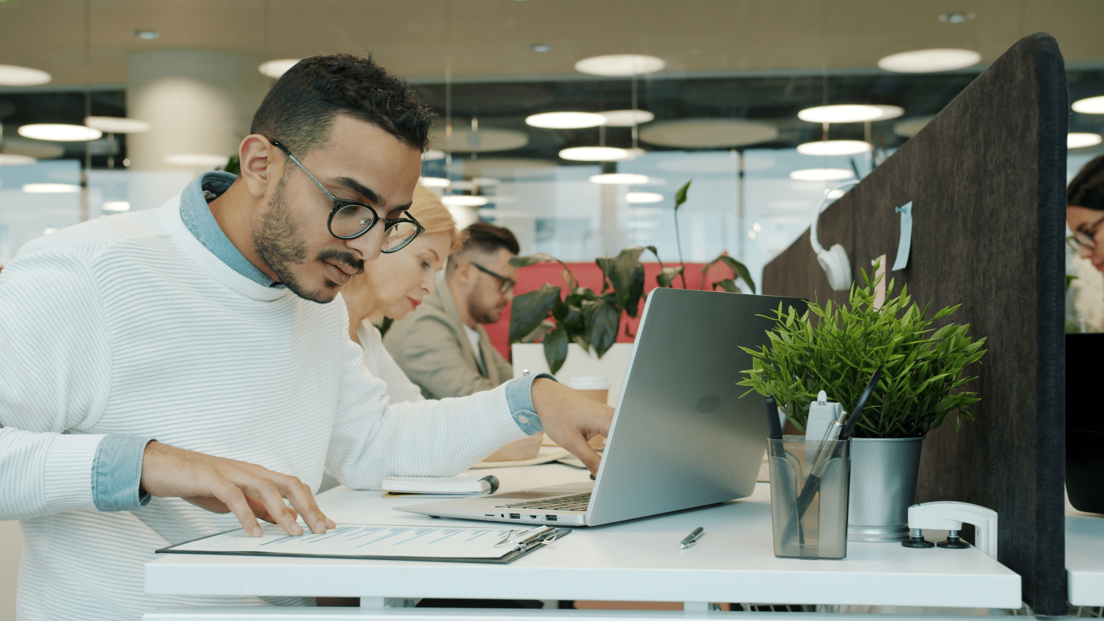 Male looking at a laptop screen in an office environment studying data